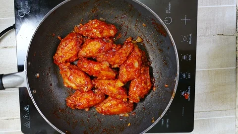 Take ripe fried chicken with red spicy chili sauce from induction pan to whit Video stock 129395622