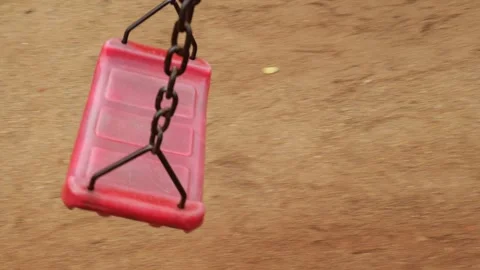 Take a slow motion along a red swing attached to an old rusty chain in the pl Video stock 203831662