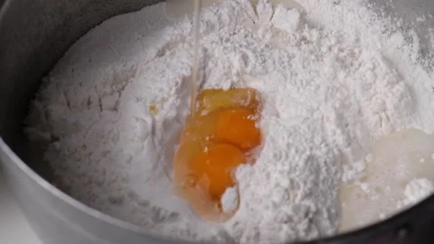 Take a slow motion shot when you crack an egg into the flour prepared for mak Stock Footage 188426842