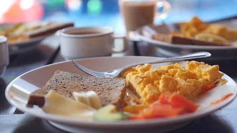 Take from the table a cup of hot coffee and milk near the plate with a delicious Stock Footage 88325182