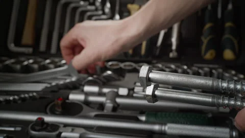 Take a wrench from the tool kit to screw a long screw into a concrete wall Stock Footage 264096177