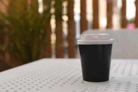 Takeaway paper cup with plastic lid on white table indoors, space for text Stock Photos