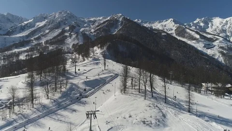Takeoff camera over the snow-capped mountains in Sochi, Rosa Khutor Stock Footage 100221079
