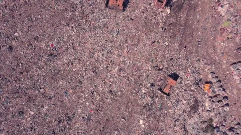 Takeoff over a garbage dump, boomerang effect, machinery works and people equal Stock Footage 137586274