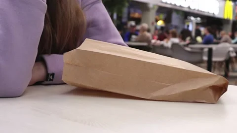 The takeout packaging paper bag for fast food on the table near the woman Stock Footage 220955459