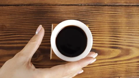 Takes a white mug of tea from the table Stock Footage 139331524