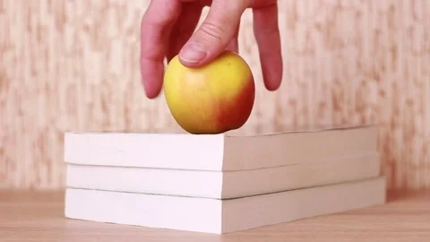 Taking an apple from the books pile Vídeos de archivo 83030223