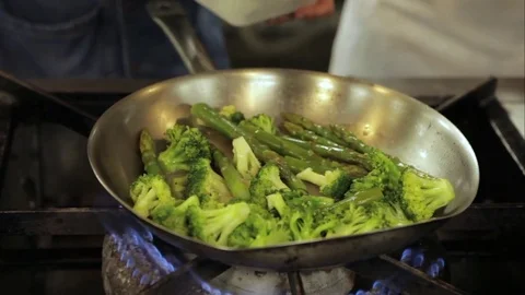 Taking asparagus and broccoli from pan Stock Footage 77760009