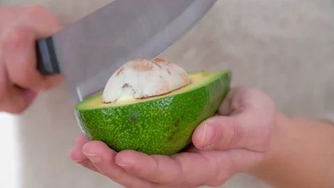 Taking avocado seed out with a big knife Stock Footage 83725277