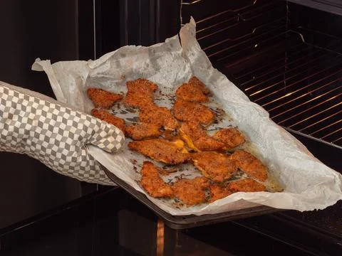 Taking baked breaded cutlets out of the oven Stock Photos