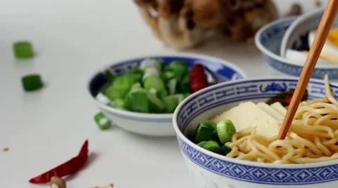Taking by bamboo chopsticks noodles from asian ramen soup with feta cheese Stock Footage 59012992