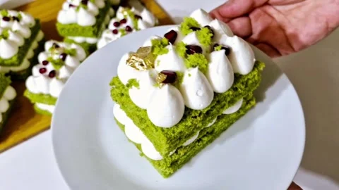 Taking a bite of decorated matcha layer cake with fork showing creamy texture 스톡 동영상 327258854