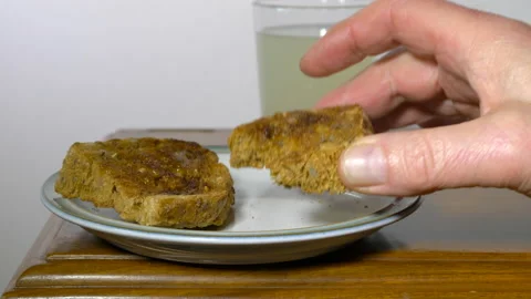 Taking a bite from a piece of buttered toast on a plate. Stock Footage 144934098