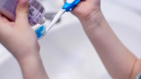 Taking care of your teeth, a little girl squeezes toothpaste on the brush Stock Footage 128651307