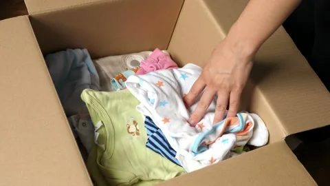 Taking checking baby clothes packed in a cardboard box Stock Footage 135240654