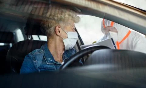 Taking corona virus test sample of senior woman in car, quarantine concept. Stock Photos