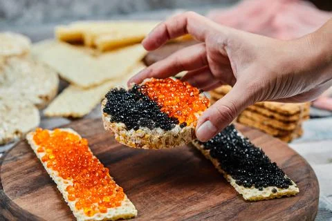 Taking a cracker sandwich with red and black caviar Stock Photos