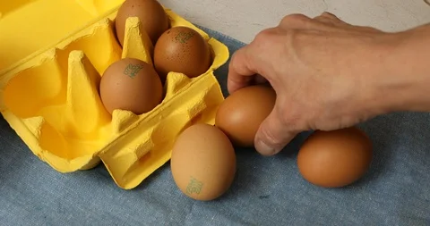Taking eggs from table with yellow paper container for eggs Stock Footage 114202083