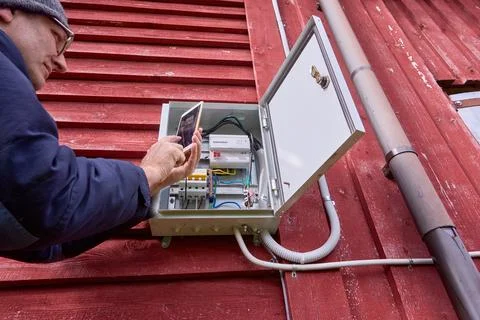 Taking electric meter readings with smartphone, homeowner takes pictures of Stock Photos