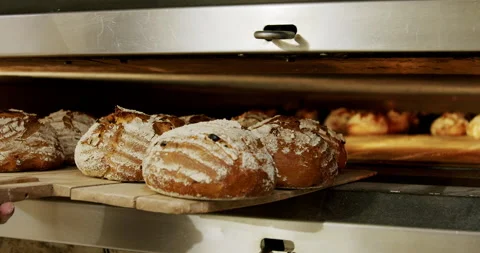 Taking freshly baked bread out of the oven 4K. Video stock 221570671