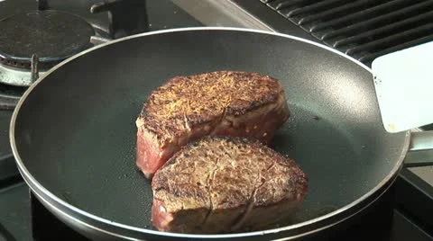 Taking fried fillet steaks out of a frying pan Stock Footage 24653684
