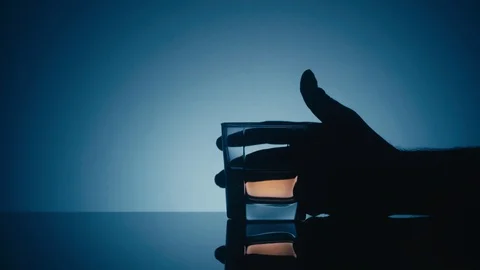 Taking a glass of whiskey on a reflective surface on a blue background Stock Footage 105286675