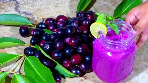 Taking java juice jar from the surface having java fruits and leafs Stock Footage 285540490