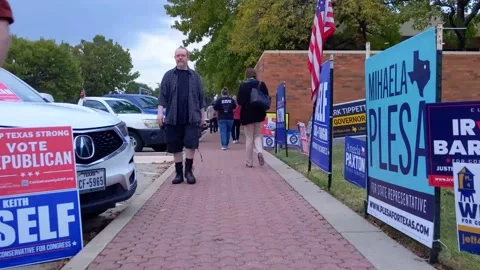 Taking a knee-level walk through candidates' yard signs outside polling location 库存影片 220815881