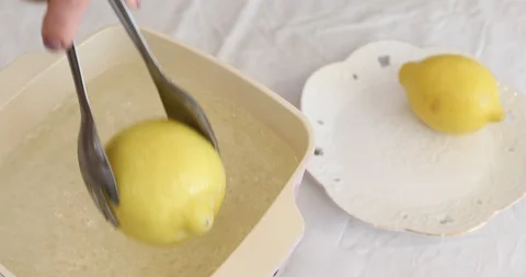 Taking lemon out of pot with boiling water Stock Footage 104594043