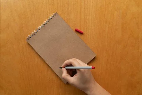 Taking notes in blank craft paper notebook. woman hand and red pencil on wood Stock Photos