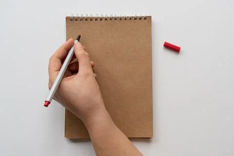 Taking notes in blank craft paper notebook. woman hand and red pencil on whit Stock Photos