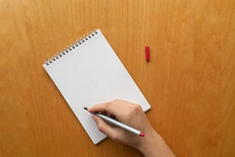 Taking notes in blank paper white notebook. woman hand and red pencil on wood Stock Photos