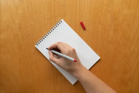 Taking notes in blank paper white notebook. woman hand and red pencil on wood Stock Photos