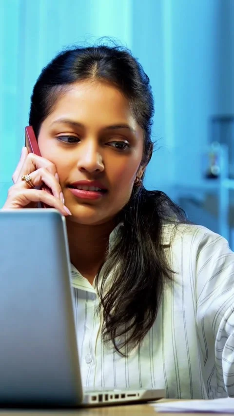 Taking notes on phone call, Indian businesswoman multitasks at desk Stock Footage 342572761