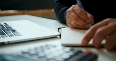 Taking notes while working on laptop Stock Footage 318799655