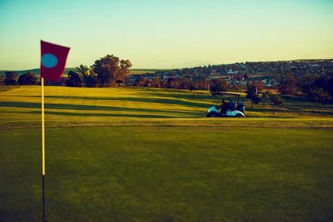Taking one tee at a time. two golfers riding in a cart on a golf course. Stock Photos