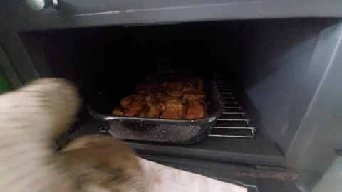 Taking out a baking pan filled with roasted pork meat pieces from a traditional Vídeo Stock 337052657