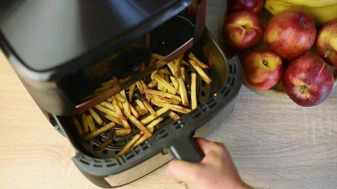 Taking out a basket with ready crispy golden french fries from air fryer Stock Footage 342322345