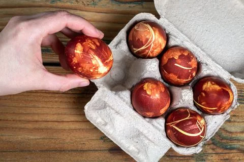 Taking out colored Easter egg from palette of eggs. Seasonal traditions Stock Photos