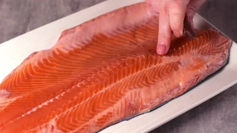 Taking out fish bones from trout with tweezers Stock Footage 230247086