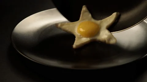 Taking out of a fried eggs in a form of a star from the pan to the dish Stock Footage 142618861
