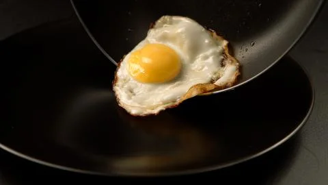 Taking out of a fried eggs from the pan to the dish Stock Photos