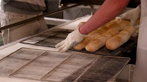 Taking out hot fresh baguettes to the iron tray. Manufacture of bread Stock Footage 64471136
