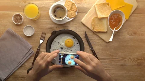 Taking picture of fried eggs with mobile phone. Phone in male hands. Top view Stock Footage 67536703