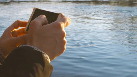 Taking a picture with a smartphone by the river at sunset Stock Footage 70739583