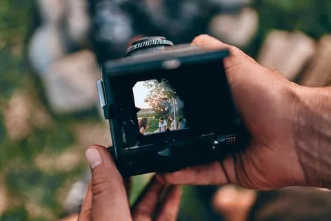 Taking a picture through the old camera on meadow with people at the picnic Stock Photos