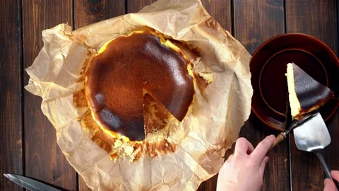 Taking a piece of basque burnt cheesecake and serving it on a plate Stock Footage 146961457
