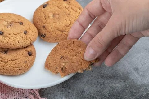Taking a piece of oatmeal cookie from white saucer Stock Photos