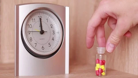 Taking pills in front of clock Stock Footage 83030432