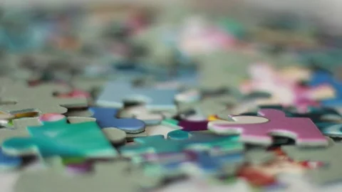 Taking puzzle pieces from a pile Stock Footage